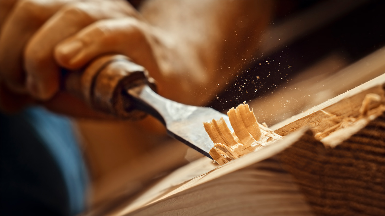 Craftsman shapes wood with chisel